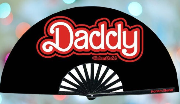 A Bamboo & Silk handheld folding fan that is Hot Pink with a Black and White Leopard Print pattern is spread open on a pink sequin background.